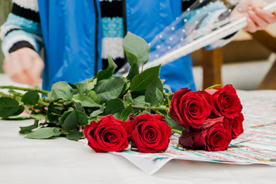 Woman florist makes bouquet of red roses. small business for gardeners. selling flowers 