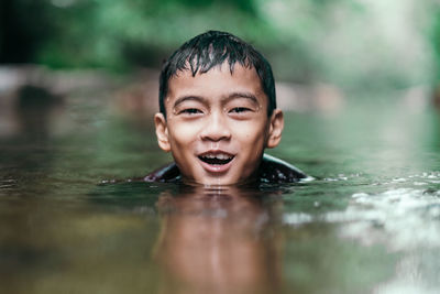 Portrait of happy boy swimming in lake at forest