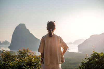 Rear view of woman looking at mountains against sky