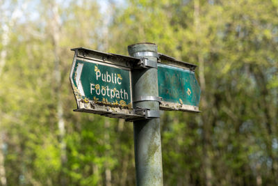 Old green public footpath sign with moss and litchen growing over