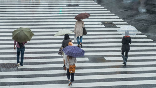 High angle view of people walking on zebra crossing during rainy season