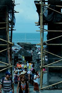 People standing by sea against sky in city