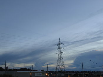 Electricity pylon in city against sky