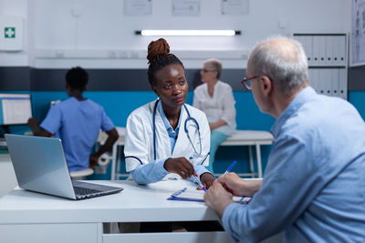 Female doctor talking to patient while filling form in hospital