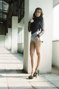 Portrait of smiling young woman standing against wall