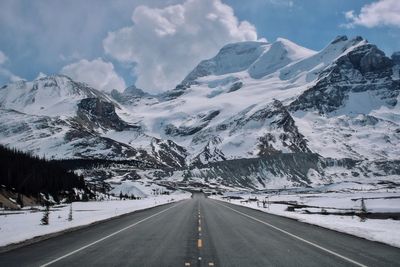 Road amidst snowcapped mountains against sky