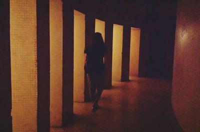 Woman walking in illuminated corridor