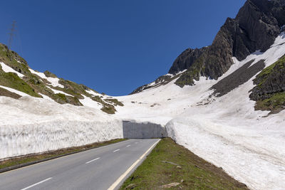 Road amidst snowcapped mountains against clear sky