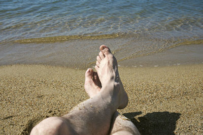 Low section of man relaxing on beach