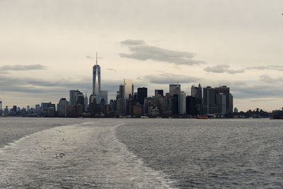 City at waterfront against cloudy sky