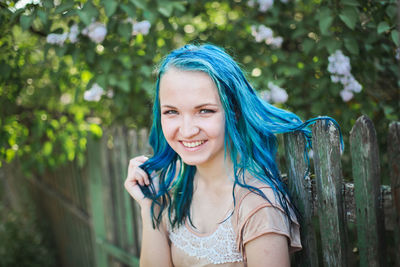 Portrait of smiling woman standing against tree