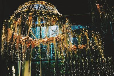 Low angle view of illuminated lights hanging on glass window
