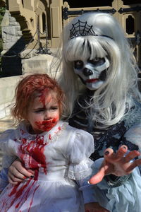 Portrait of woman holding girl with spooky make-up during halloween