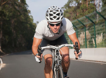 Full length of man riding bicycle on road by railing