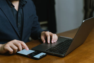 Midsection of businessman using laptop on table