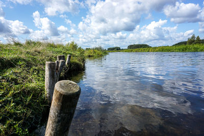 Wooden post in lake against sky