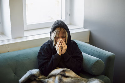 Ill woman on sofa blowing nose