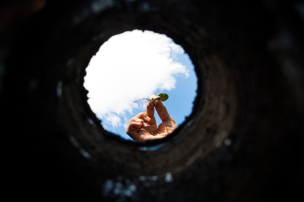 REFLECTION OF PERSON IN SKY SEEN THROUGH HOLE IN THE DARK