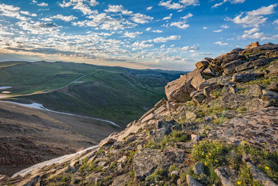 Scenic view of landscape against cloudy sky during sunset