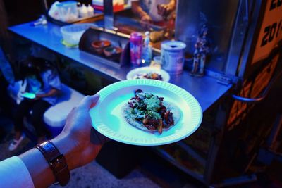 Cropped image of man holding taco in plate at food stall