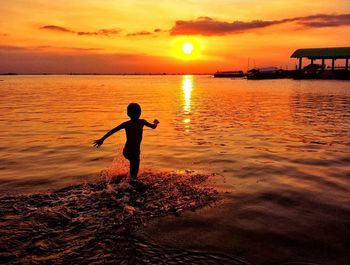 Silhouette of man standing on beach at sunset