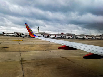 Airplane on airport runway against cloudy sky