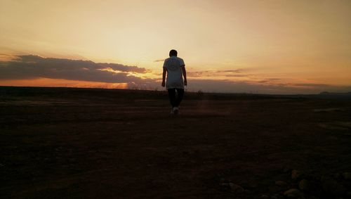 Rear view of silhouette man standing on field against sky