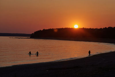 Silhouette people on beach during sunset