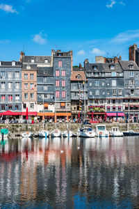 Sailboats moored on river by buildings in city against sky