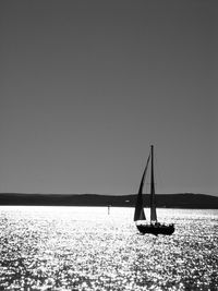 Sailboat sailing on sea against clear sky