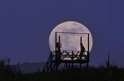 Silhouette gazebo on field against sky at night