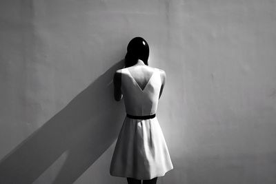 Rear view of woman standing against white wall
