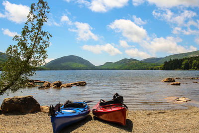 Kayaks at beach against cloudy sky during sunny day at acadia national park