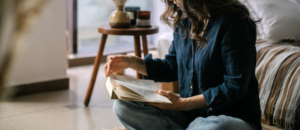 Woman reading book sitting at home