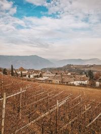 High angle view of field and village against cloudy sky