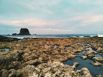 Scenic view of beach and rocks against sky