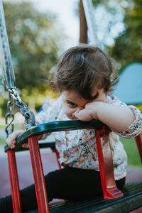 Portrait of baby girl sitting on swing at park