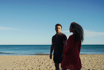 Side view of woman opposite to man standing at beach