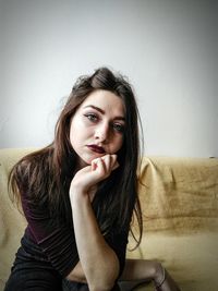 Portrait of beautiful young woman sitting on sofa at home