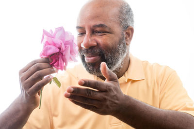 Portrait of man holding flower against white background