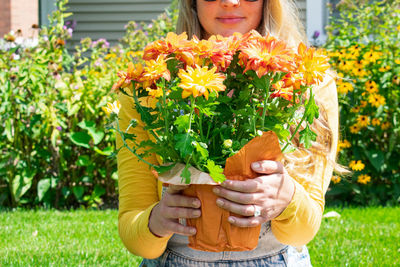 Midsection of woman holding flowering plants