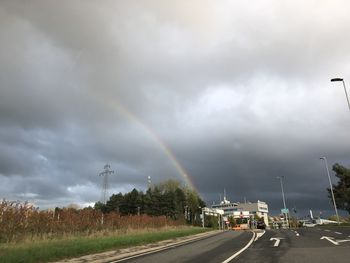 Rainbow over road against sky