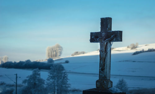 Close-up of cross against blue sky during winter