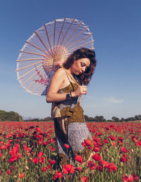 Young woman standing on field against sky
