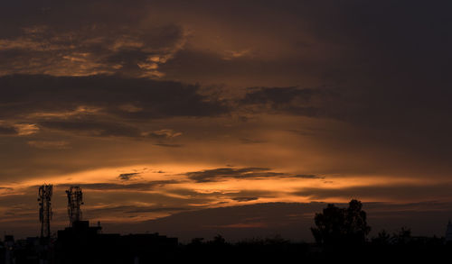 Silhouette of communication tower and trees against sky during sunset