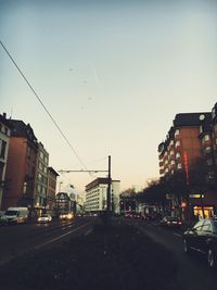 Cars on street in city against clear sky