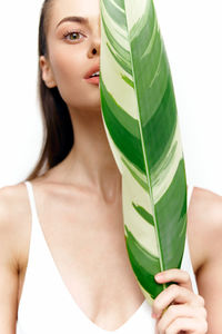 Midsection of woman holding feather against white background