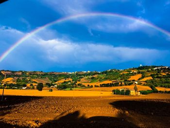 Scenic view of field against rainbow in sky