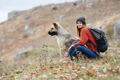 Woman with dog sitting on land