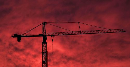 Low angle view of silhouette crane against sky during sunset